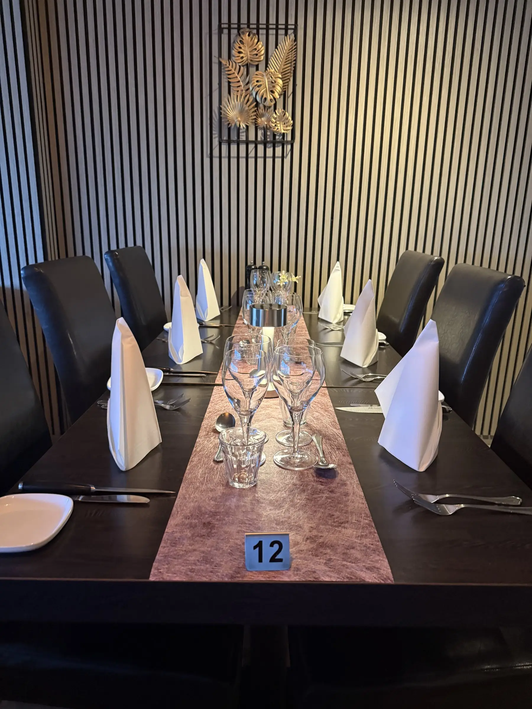 Dækket bord nummer 12 i restauranten med hvide servietter og vinglas