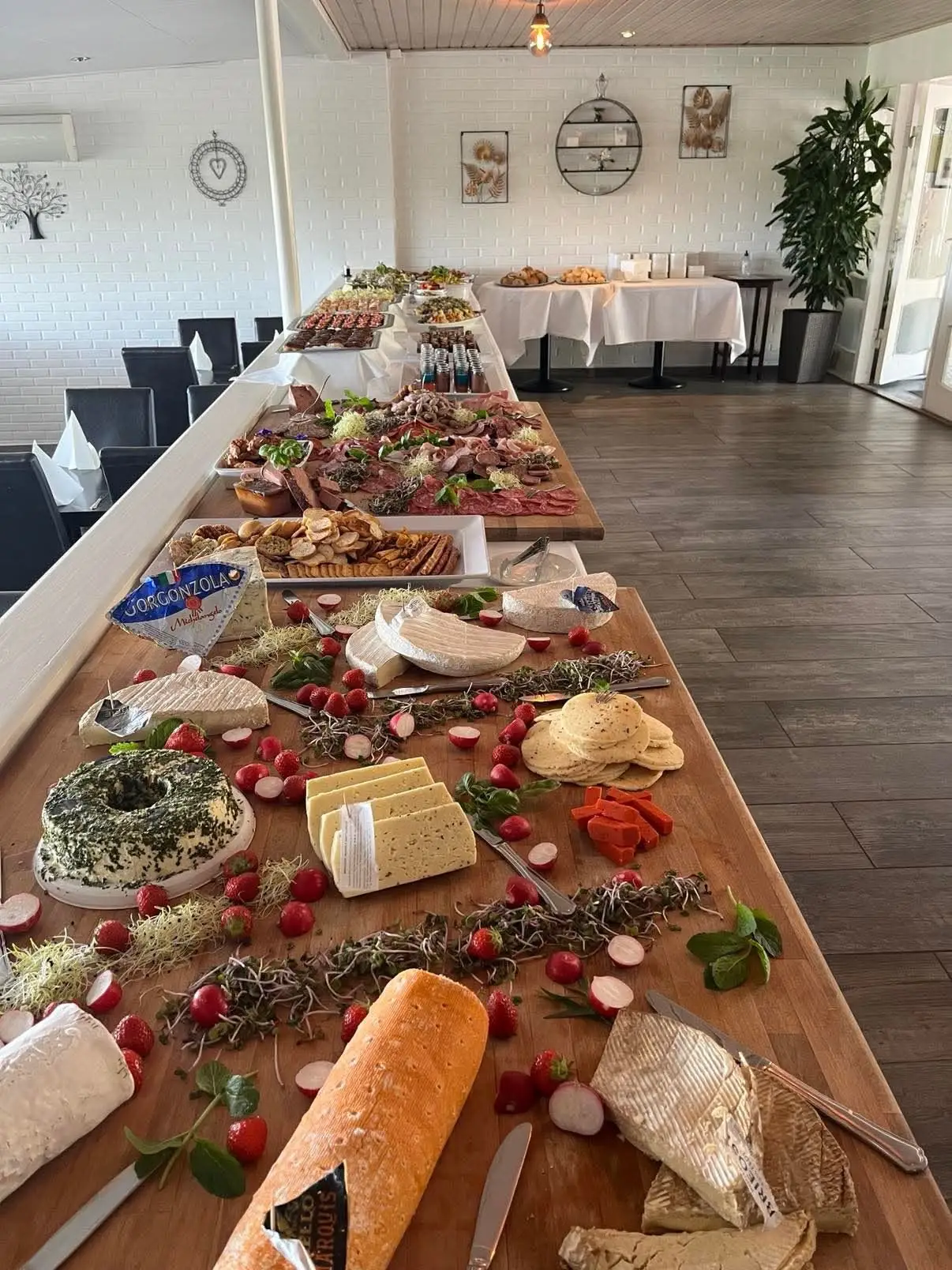 Brunchbuffet med brød, oste, pålæg og pynt på et langt træbræt
