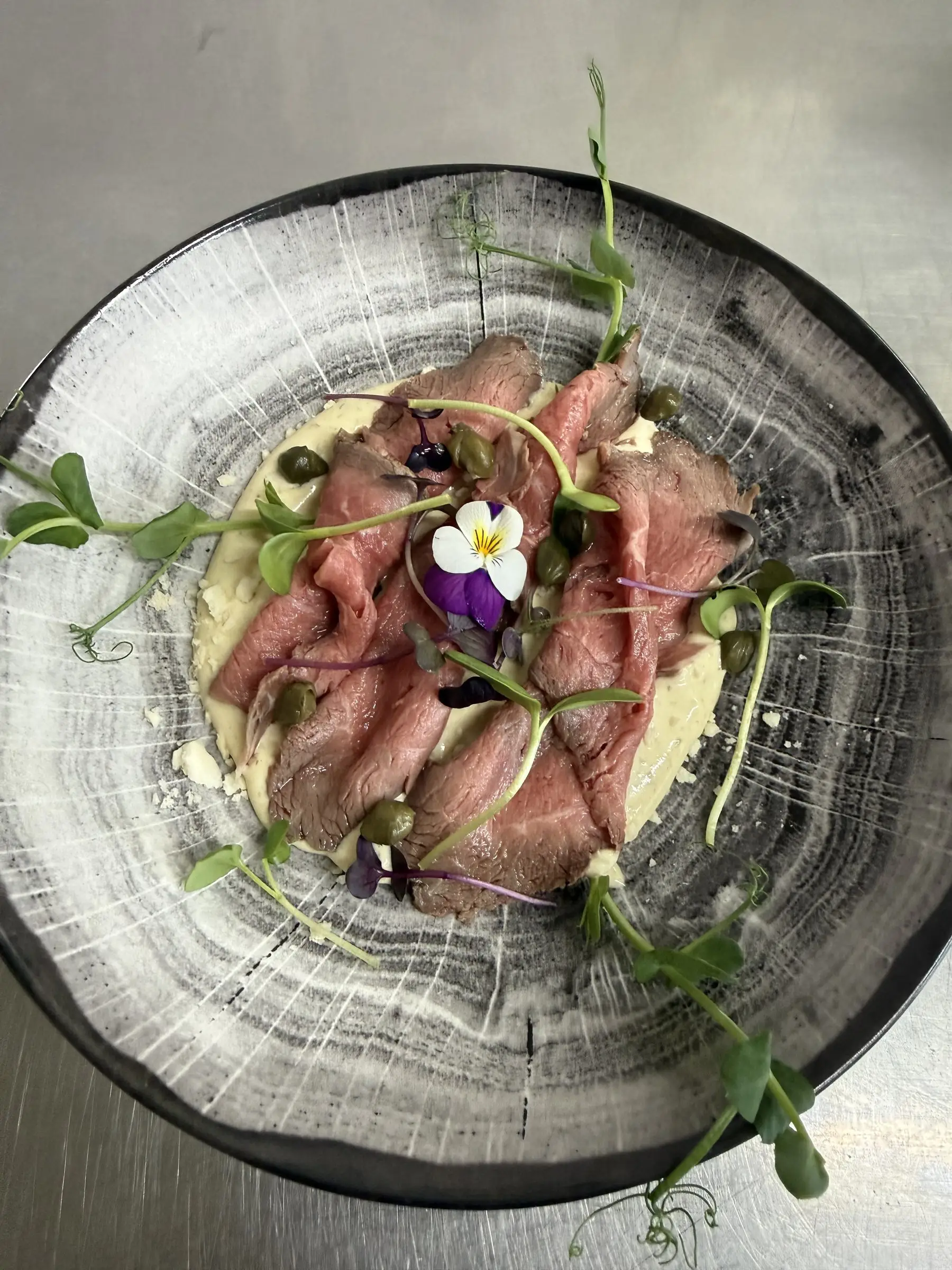 Oksecarpaccio med kapers, spirer og en spiselig blomst