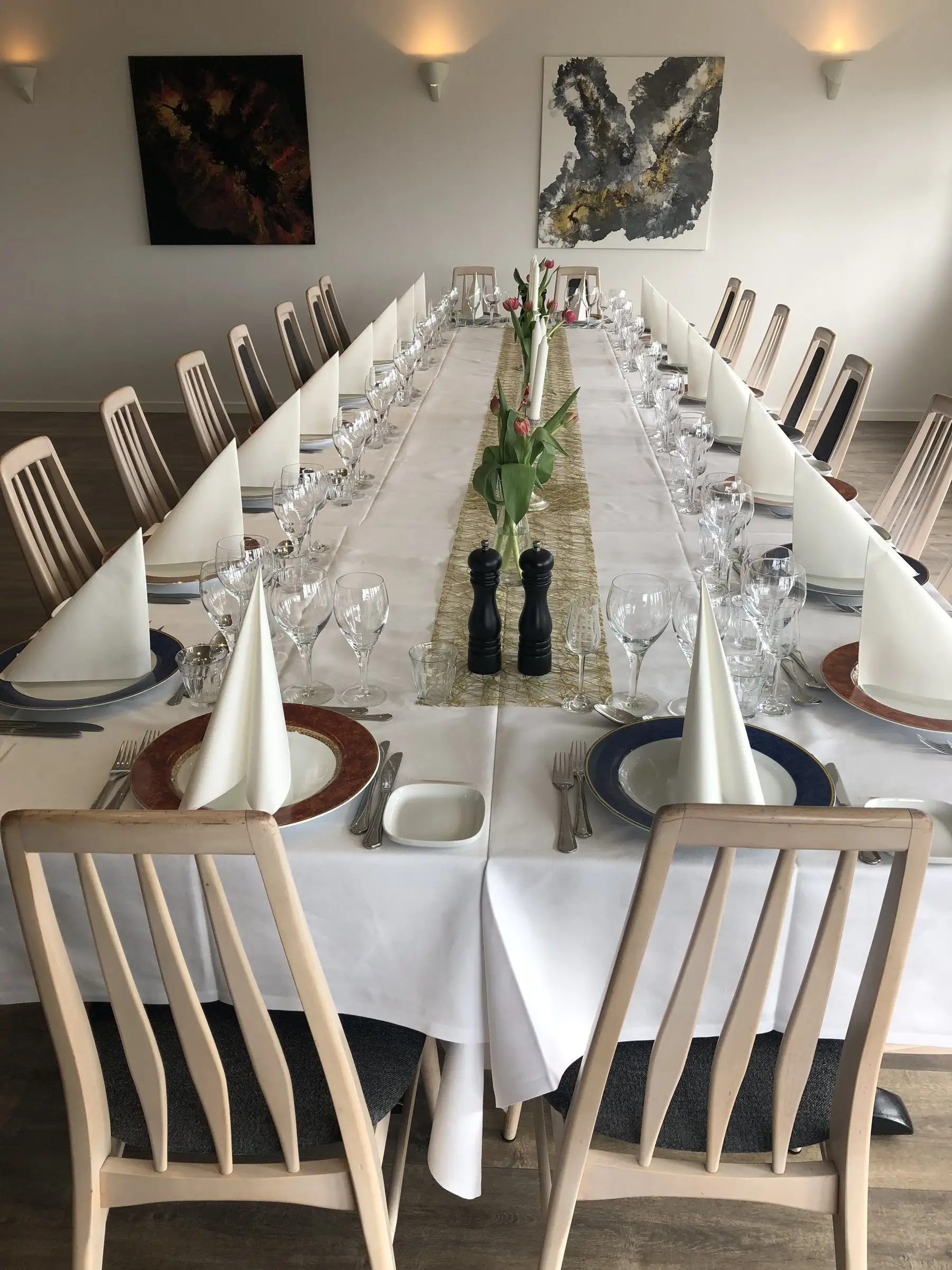 Langt festbord med tulipaner, vinglas og foldede servietter