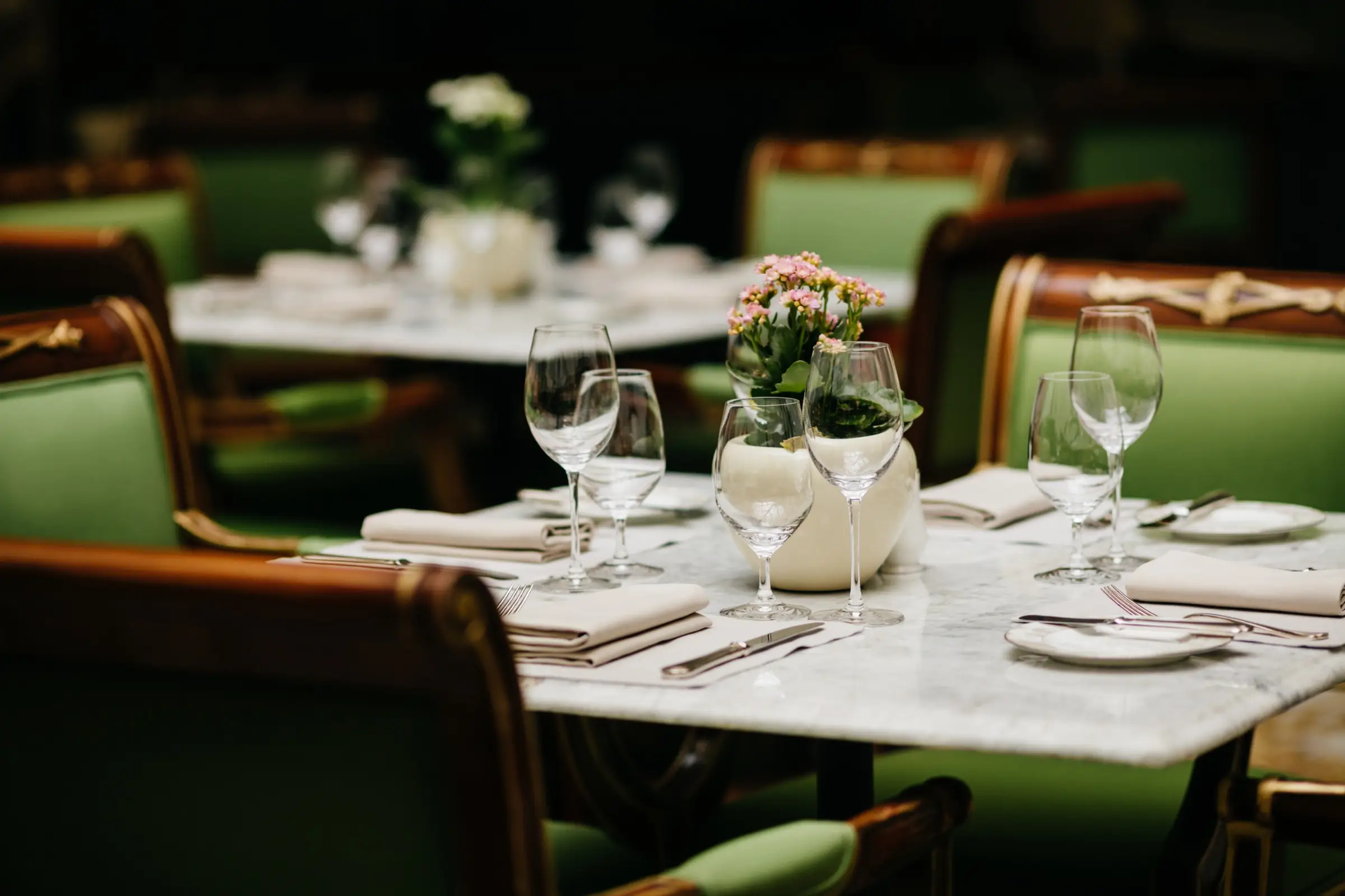 Dækket selskabsbord med vinglas, foldede servietter og blomster