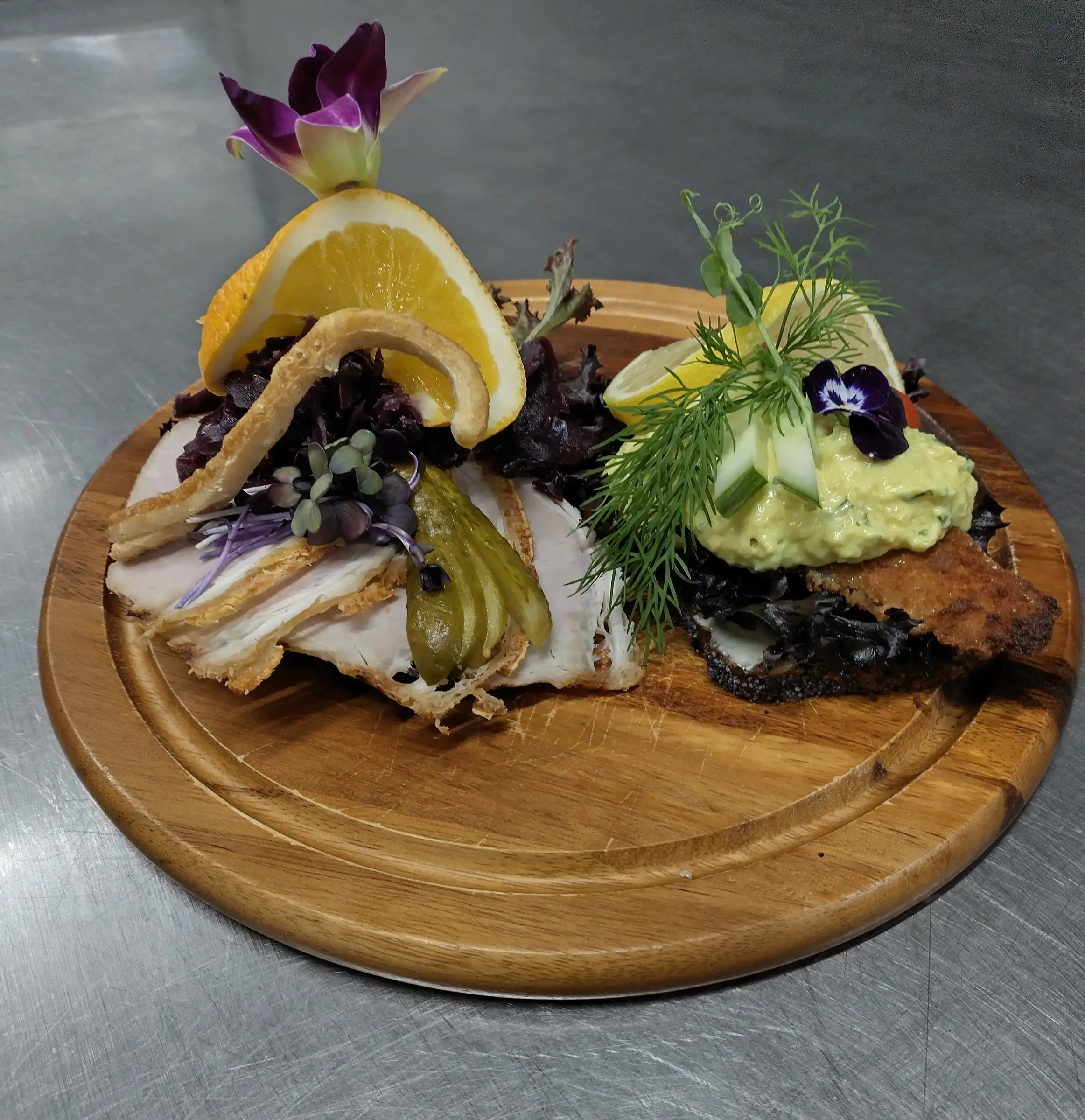 Smørrebrød på et træbræt med appelsin, agurk og dild