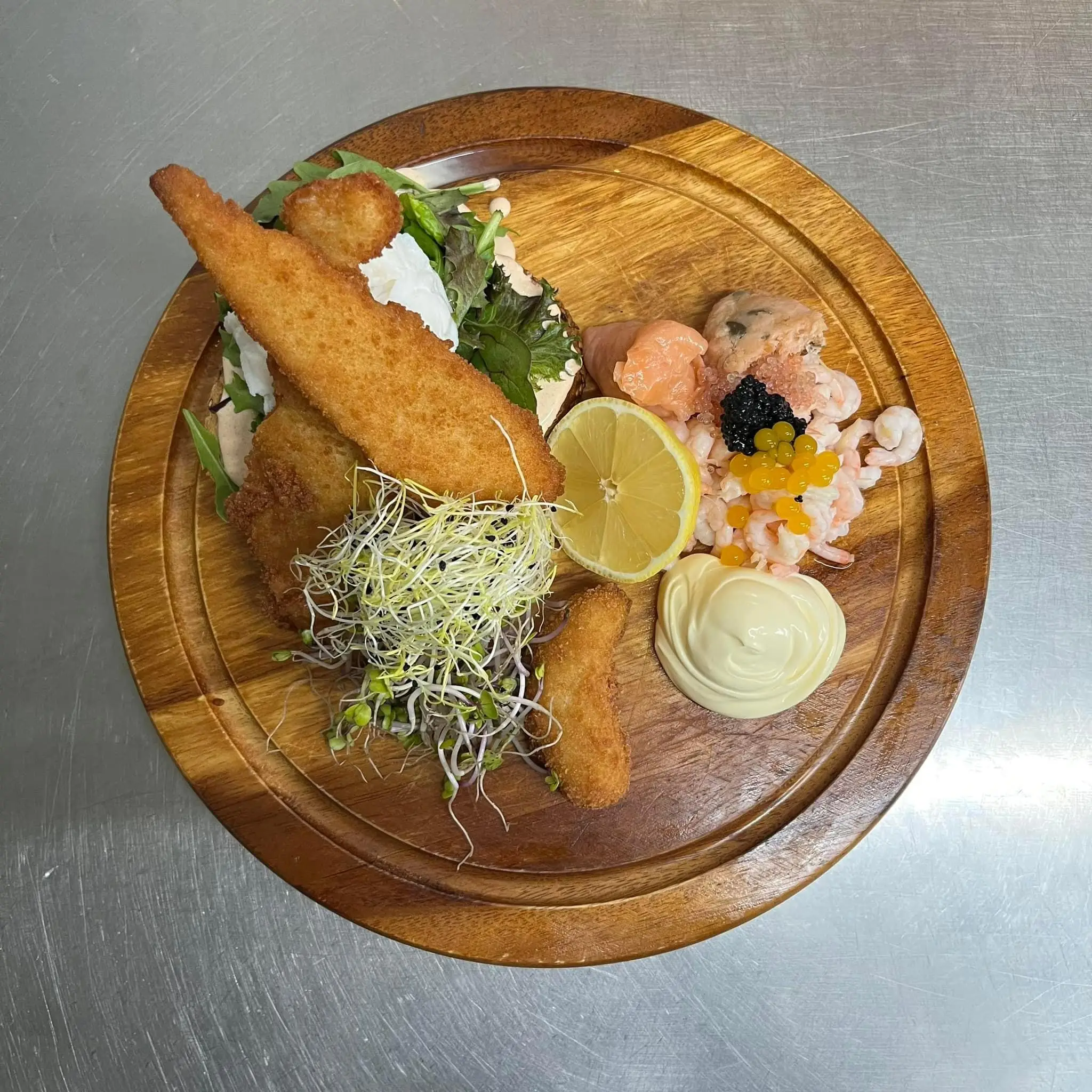 Luksus stjerneskud med fiskefilet, rejer, kaviar og citron på et træbræt