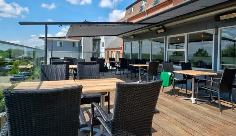 Terrassen langs huset med borde og stole i solskin