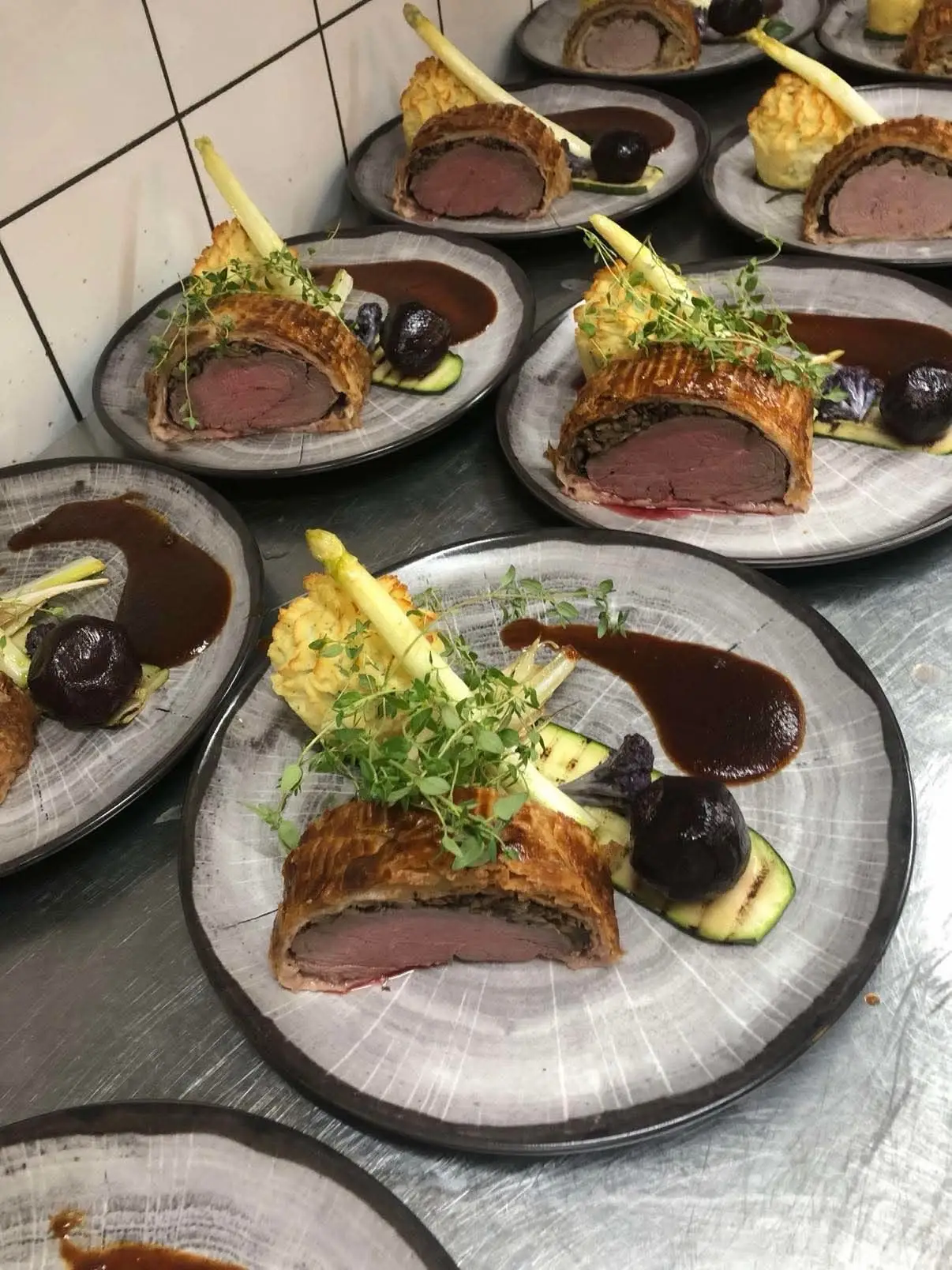 Beef Wellington anrettet på række med rødvinssauce og asparges